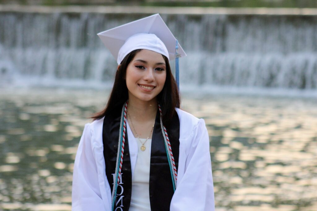 ACC student posing in white cap and gown