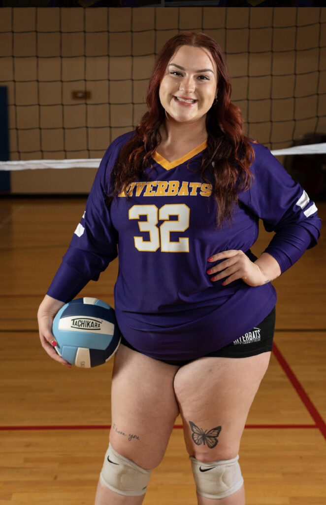 Picture of ACC student Adia posing in front of volleyball net and holding volleyball