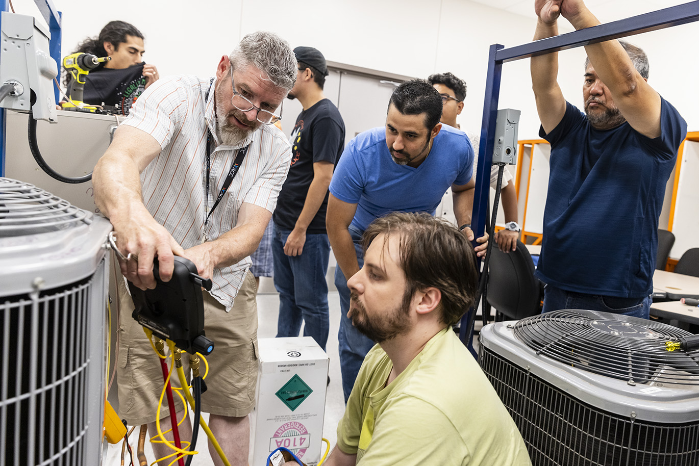 A college instructor trains students on how to operate Heating, Ventilation and Air Conditioning maintenance and repair equipment.