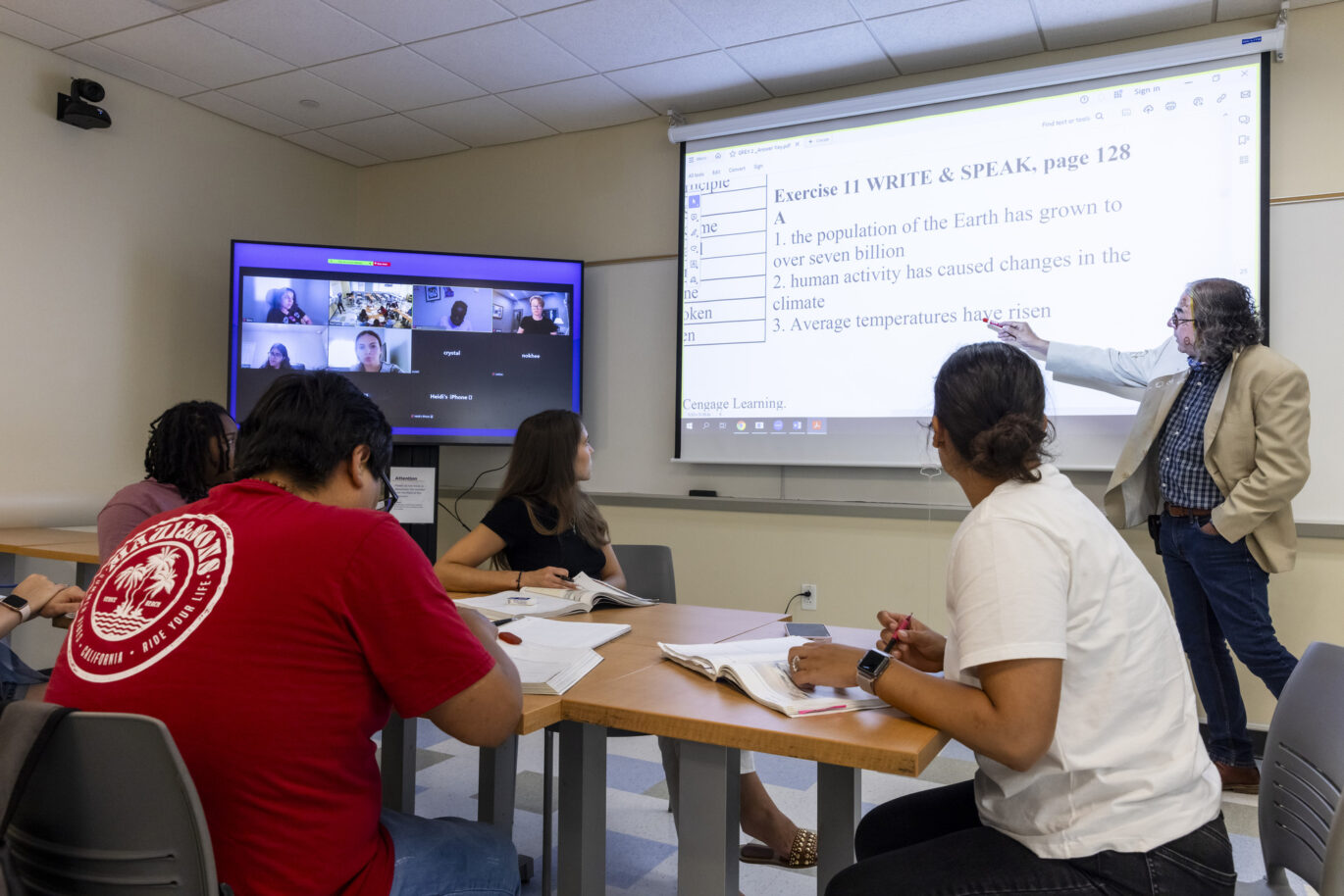 A college instructor teaches lecture to an in-person and online student audience.