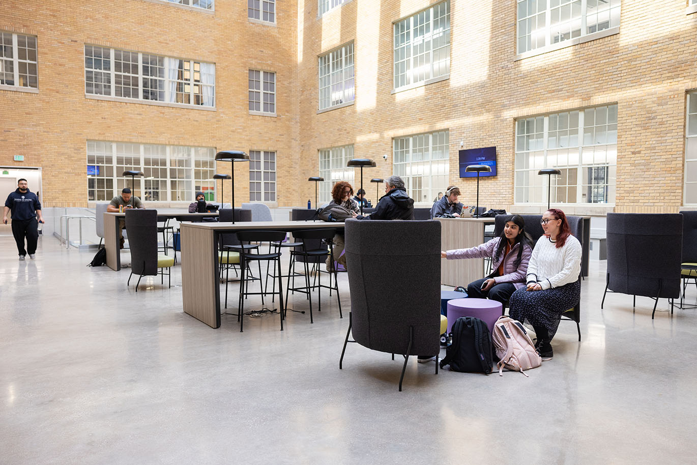 Multiple ACC students are seen studying or engaging with each other in an interior covered courtyard, known as an atrium, at the Rio Grande Campus.