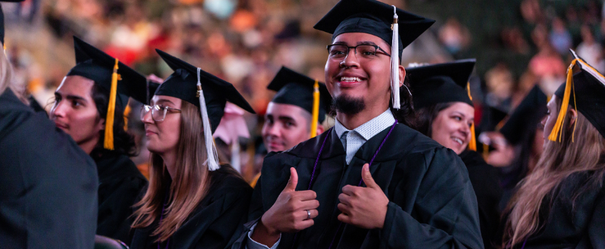 Smiling ACC student with both thumbs up at Commencement.