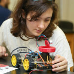 An engineering student works with a robotic car in class.