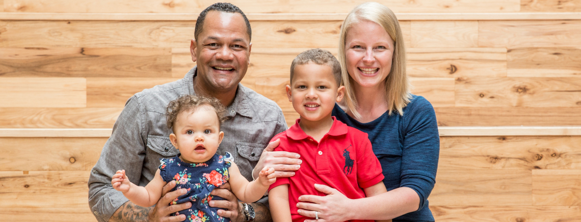 A family of four, including a man, woman, and two kids, poses happily at the ACC Highland Social Staircase